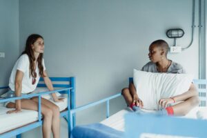 Deux femmes sont assises et discutent tranquillement sur des lits superposés dans une chambre d'auberge.
