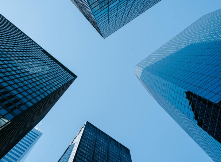 Faible angle de hautes tours d'affaires avec des fenêtres en verre miroir situées dans la mégalopole du centre-ville contre le ciel bleu